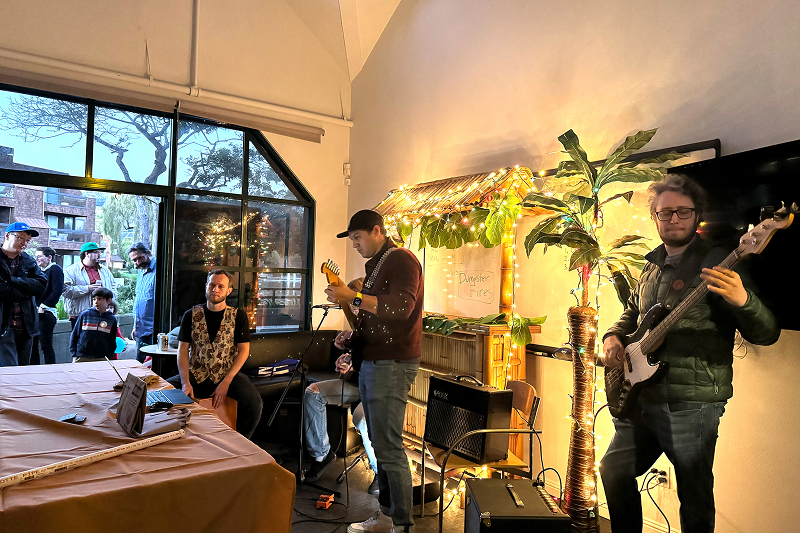 3 musically-talented Digital foundry consultants and engineers play a guitar, bass and cajón box drum at the digital foundry holiday party