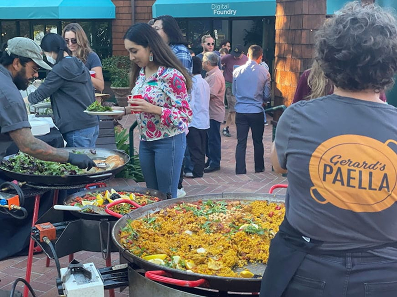 A female digital foundry software consultant heads up the food line with a plate at the annual digital foundry paella party.